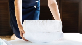 Camarera de piso colocando toallas en la habitación de un hotel