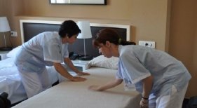 Camareras de piso (kellys) agachadas haciendo una cama en la habitación de un hotel 