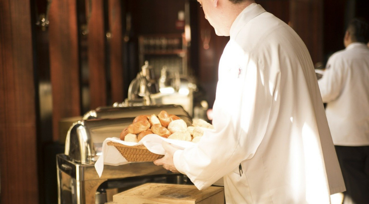 Camarero profesional repone pan en un buffet