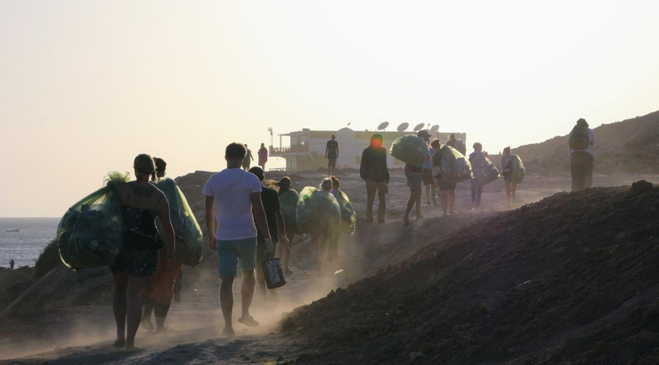 Turistas recogen basura de una playa como parte del turismo regenerativo