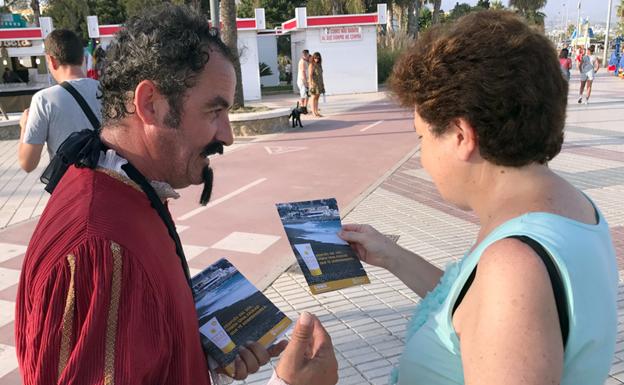 Un actor que representa a Cervantes entrega un folleto a una visitante en Vélez-Málaga