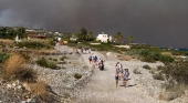 Turistas camino de ser evacuados en una playa de Rodas (Grecia)