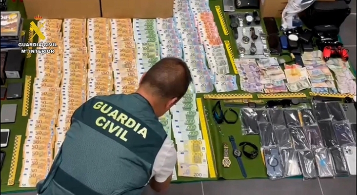 Un agente de la Guardi Civil manipulando los objetos y el dinero en efectivo robado en el Aeropuerto de Tenerife Sur | Foto: Ministerio del Interior