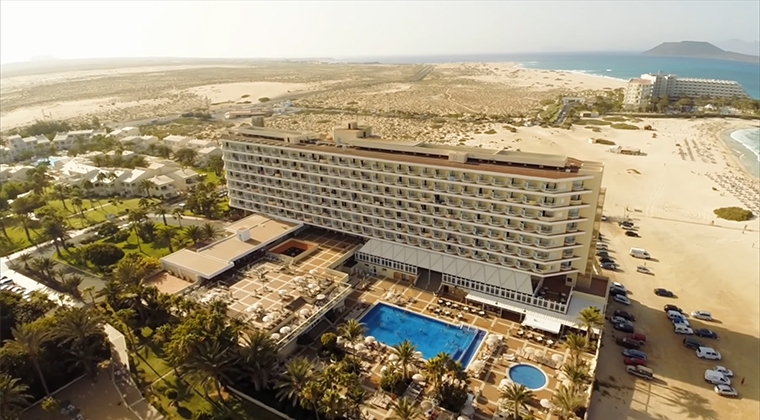 El edificio principal del complejo RIU Oliva Beach Resort, con el hotel RIU Palace Tres Islas al fondo, ambos sobre las dunas del Parque Natural de Corralejo, en Fuerteventura | Foto: RIU